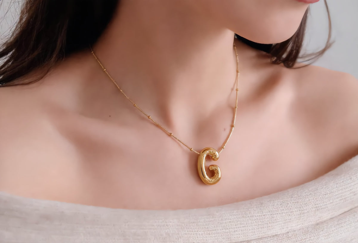 Gold initial necklace G worn on the neck